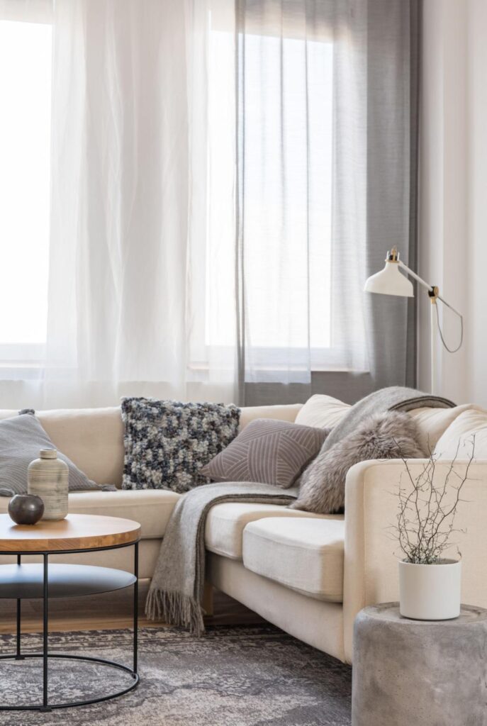 Cozy neutral living room with soft sofa, pillows, natural light and minimalist decor