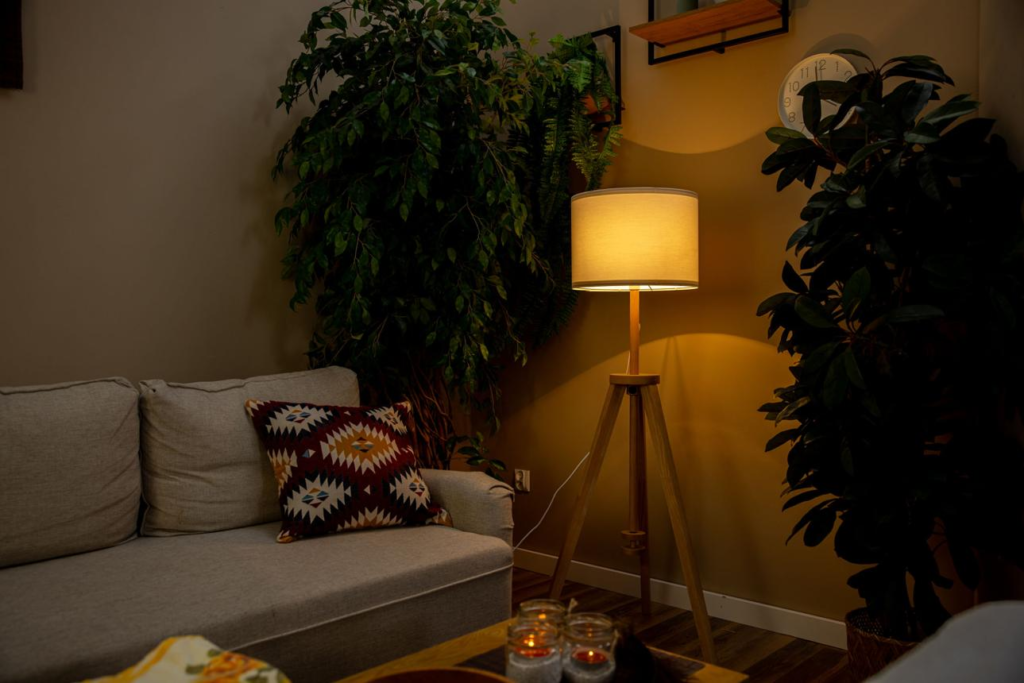 Cozy living room interior with warm lamp lighting, sofa and green plants